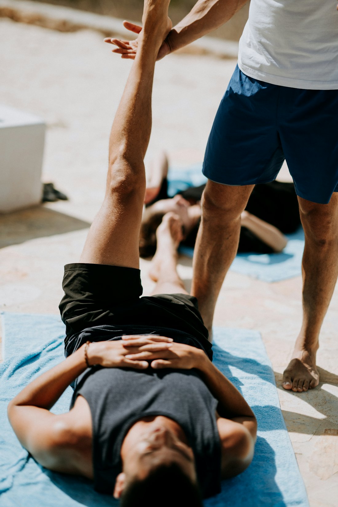A trainer helping a client through a leg stretch outdoors